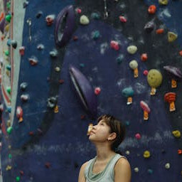 woman in gym attire looking at a climbing wall